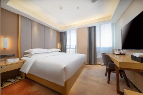 a hotel room with a bed and a desk and a computer at Guangzhou Baiyun Airport Yunzhi Hotel near Terminal One in Guangzhou