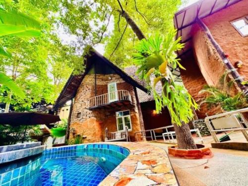 a house with a swimming pool in front of it at Hern Lhin Natural Resort in Ban Pong