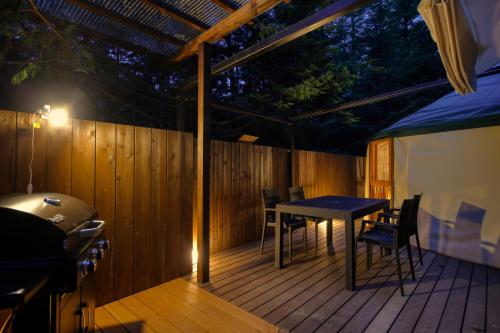 a patio with a table and chairs on a wooden deck at Altitude939 -アルティチュード939- in Fujiyoshida