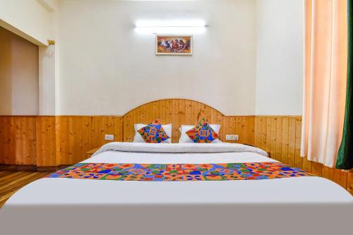 a bedroom with a large bed with a wooden headboard at FabHotel Suvidha Cottage in Manāli
