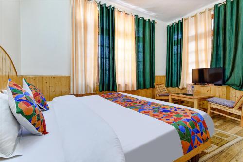 a bedroom with a white bed and a television at FabHotel Suvidha Cottage in Manāli