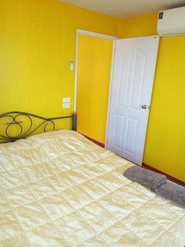 a bedroom with a bed with yellow walls and a white door at HomeState Bang Maprao in Ban Hin Sam Kon
