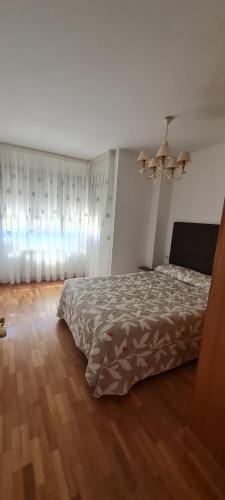 1 dormitorio con cama y lámpara de araña en Apartamento Bulevar, en Burgos