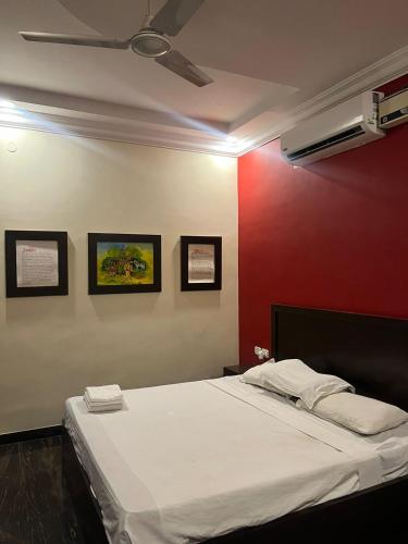 1 dormitorio con cama blanca y pared roja en THE ALP HOTEL Bypass Road, en Madurai