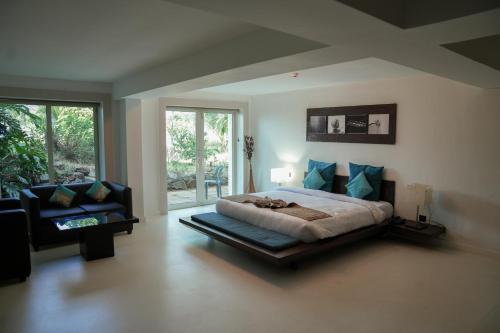 a bedroom with a bed and a couch in it at Beach House Resort Goa in Benaulim