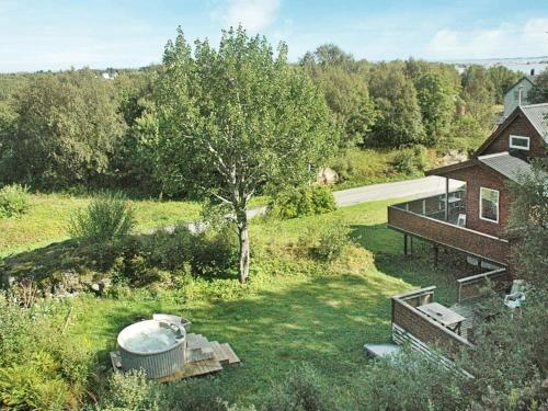 Vevangにある5 person holiday home in VEVANGのホットタブと家のある裏庭の景色を望めます。