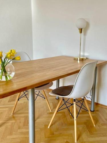 una mesa de madera con 2 sillas y un jarrón de flores en Your bright city gem in Leipzig en Leipzig
