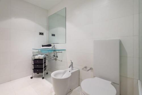 a white bathroom with a toilet and a sink at 3bedroom Duplex with balcony in plaza Cataluña in Barcelona