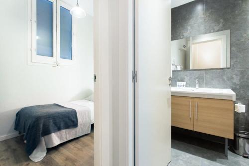 een badkamer met een bed, een wastafel en een spiegel bij Bright and modern 2bedroom in Las Ramblas 2 1A in Barcelona