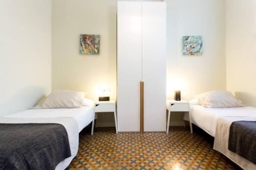 2 camas en una habitación con paredes blancas y 2 mesas en 4bedroom apart with balcony in Las Ramblas 3-2, en Barcelona