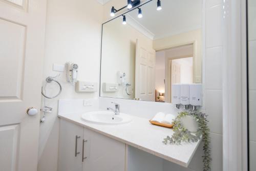 ein weißes Badezimmer mit einem Waschbecken und einem Spiegel in der Unterkunft Best Western Tuscany on Tor Motor Inn in Toowoomba