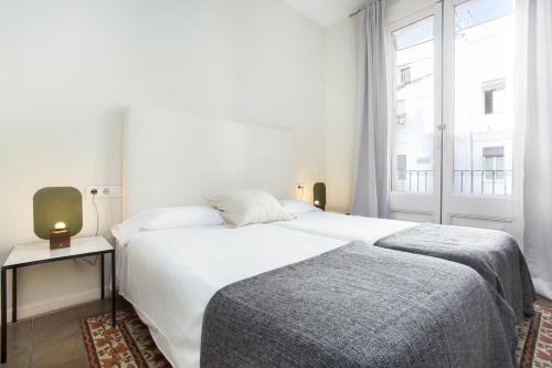 4 bedroom apartment with a balcony in Las Ramblas 2 2 في برشلونة: غرفة نوم بسرير ابيض كبير ونافذة