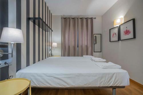 a bedroom with a large white bed and a table at Modern and bright apartment in Eixample 5-2 in Barcelona