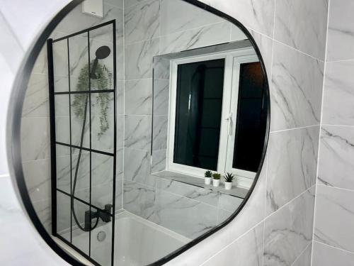 a mirror in a bathroom with a window at Cosy 4 Bed House in Aldershot