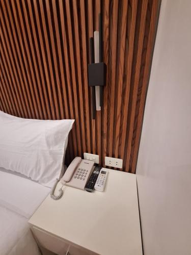 Casa Ison Hotel في Sablayan: سرير مع هاتف فوق طاولة