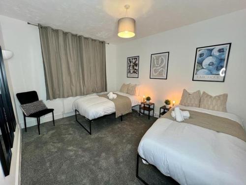 a hotel room with two beds and a couch at Cosy 4 Bed House in Aldershot