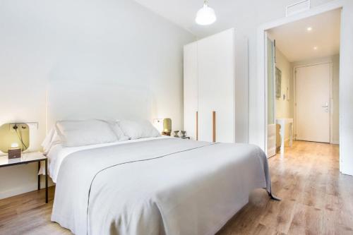 a white bedroom with a large white bed and a desk at Centric 2bedroom in Las Ramblas 3 1A in Barcelona