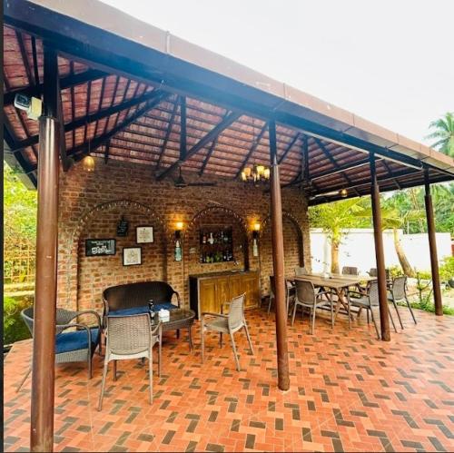 eine Terrasse mit Tischen und Stühlen unter einem Backsteingebäude in der Unterkunft Opal Oasis Villa in Alībāg