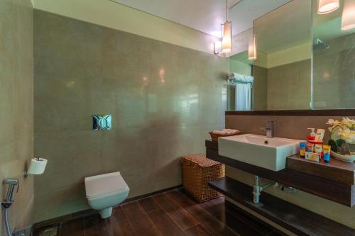 a bathroom with a sink and a toilet and a mirror at StayVista at Moksh Villa in Alibaug