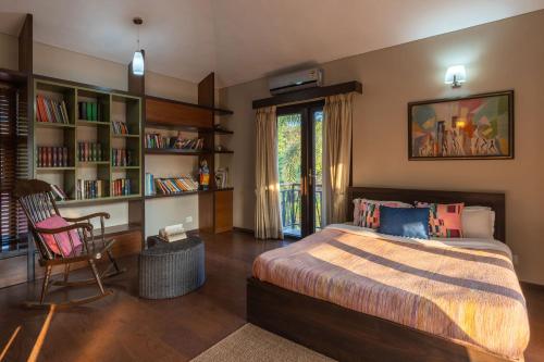 a bedroom with a bed and a desk and book shelves at StayVista at Moksh Villa in Alibaug
