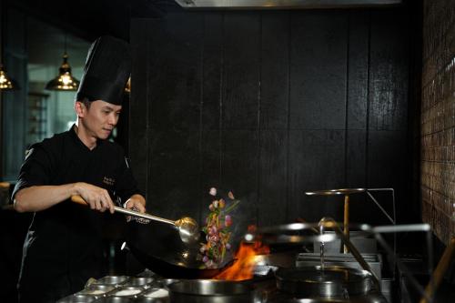 a man in a chefs hat stirring a pot on a stove at JW Marriott Hotel Kolkata in Kolkata