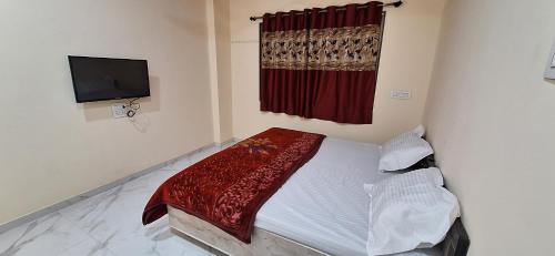 Savali Lodging and Boarding في Chālisgaon: غرفة نوم صغيرة بها سرير وتلفزيون