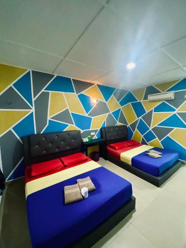a room with two beds and a colorful wall at Abot guest house in Kuala Tahan