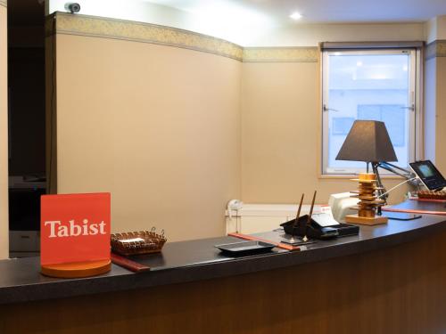 an office with a table with a sign on it at Tabist Hirosaki Touei Hotel in Hirosaki