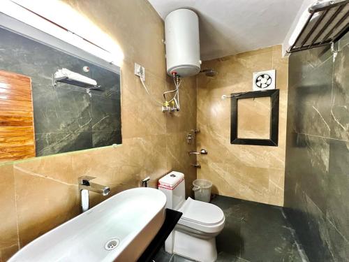 ein Badezimmer mit einem weißen Waschbecken und einem WC in der Unterkunft Hotel Majestic Grand in Shimla