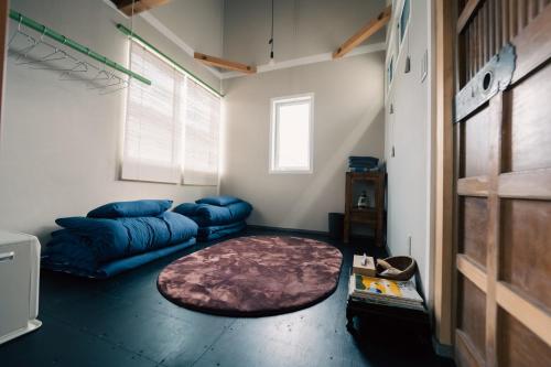 sala de estar con sofá azul y alfombra en 宿と古道具 iyooo, en Nanao
