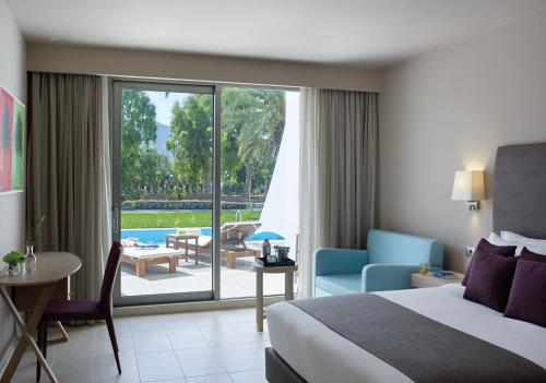 a hotel room with a bed and a view of a patio at Atlantica Akti Zeus Hotel in Amoudara Herakliou
