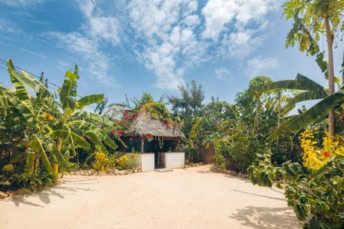une petite maison avec un toit de chaume dans un jardin dans l'établissement Bukoba Villas - Lily - Private Pool, AC & Wi-Fi, à Nungwi