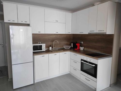 a white kitchen with white cabinets and a microwave at DiP HOME APARTMENTS in Pomorie