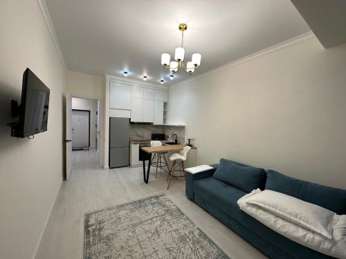 sala de estar con sofá azul y cocina en 2-комнатные апартаменты в новом жилом комплексе, en Almaty