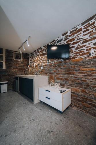 a room with a brick wall with a tv on the wall at Tramontana Suites in Áyios Stéfanos