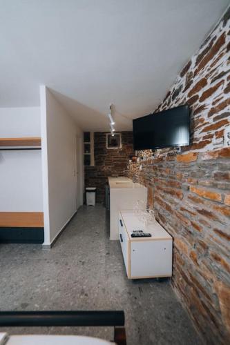a room with a brick wall and a tv on a wall at Tramontana Suites in Áyios Stéfanos