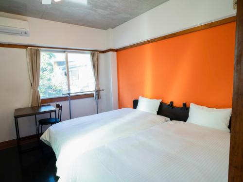two beds in a room with an orange wall at 恩納Garden Resort Okinawa 希望が丘ビーチまで徒歩10分 in Inbu