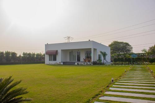 a small white house in a field of grass at The Peace- A Luxury Pool Villa in Jaipur