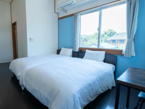 a bedroom with a large white bed and a window at 恩納Garden Resort Okinawa 希望が丘ビーチまで徒歩10分 in Inbu