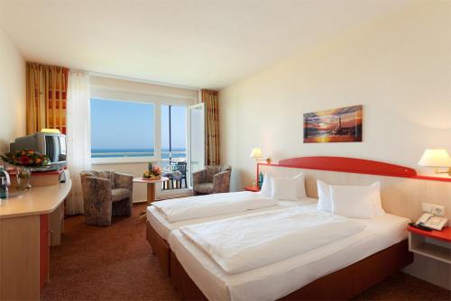 um quarto de hotel com uma cama grande e uma janela grande em Morada Resort Kühlungsborn em Kühlungsborn