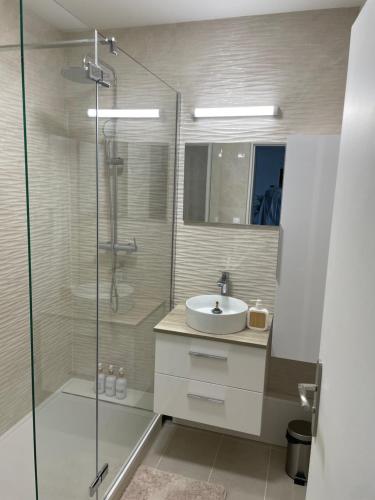 ein Bad mit einem Waschbecken und einer Glasdusche in der Unterkunft Coliving - chambre jaune in Sarcelles