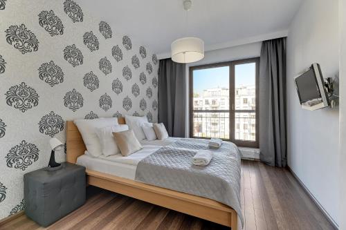 sypialnia z łóżkiem i dużym oknem w obiekcie Szafarnia DeLuxe Apartment Apartinfo w Gdańsku