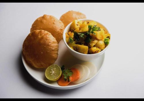 un piatto di cibo con una ciotola di zuppa e pane di Hotel Wonderland Inn Medanta a Gurgaon