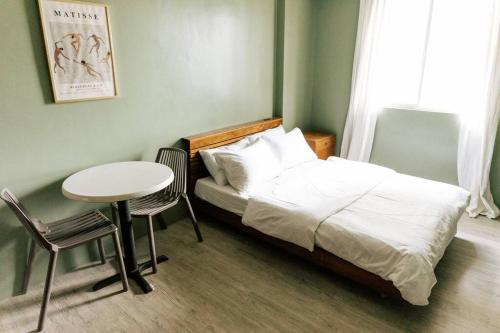 a bedroom with a bed and a table and chair at Siesta Studio in Bacolod