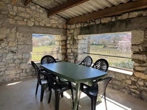 une table et des chaises dans une pièce avec un mur en pierre dans l'établissement Maison de Campagne au bord de l'eau, à Saint Alban Auriolles