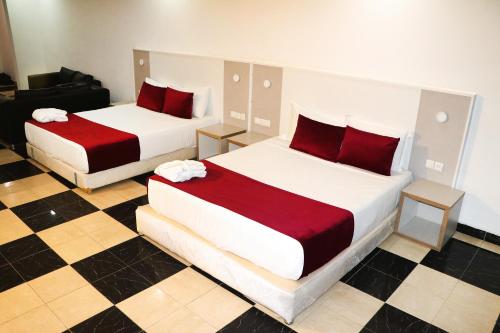 2 camas con almohadas rojas en una habitación en Hotel Hayatt Atlantique, en Nouakchott