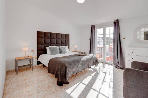 a white bedroom with a large bed and a window at Nice House Nina With Jacuzzi in Playa de San Juan