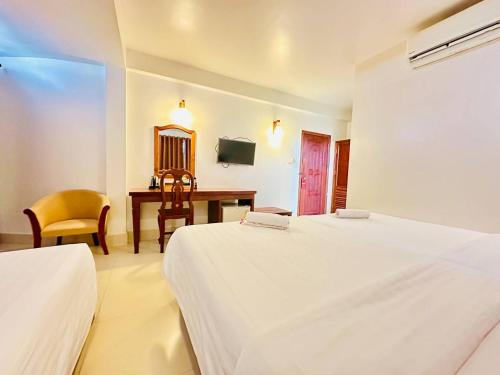 a bedroom with two beds and a desk and a table at Holy Angkor Hotel in Siem Reap