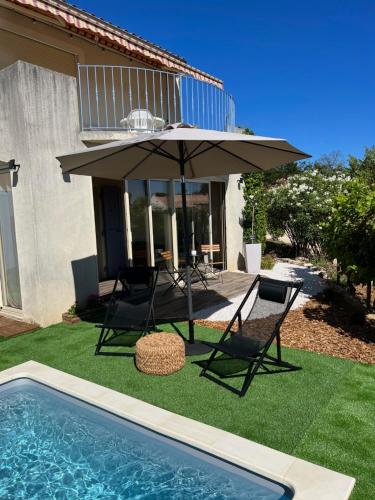 eine Terrasse mit einem Sonnenschirm und Stühlen sowie einem Pool in der Unterkunft Appartement cocooning & love in Allex