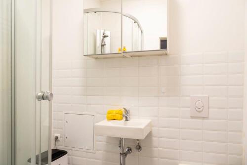 een witte badkamer met een wastafel en een spiegel bij Cosy Two BR plus Self Checkin plus Street Parking in Berlijn